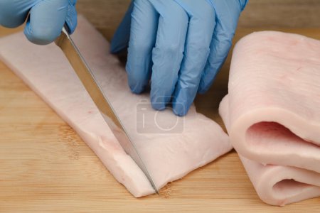 Fat is cut into small pieces. Hands of a cook cutting lard with a knife into small pieces to prepare food. home cuisine
