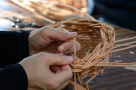 Photo for Hands of a folk craftsman weaving a traditional wicker basket in close-up - Royalty Free Image