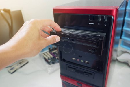 Photo for Man's hand inserting CD-ROM into computer case - Royalty Free Image