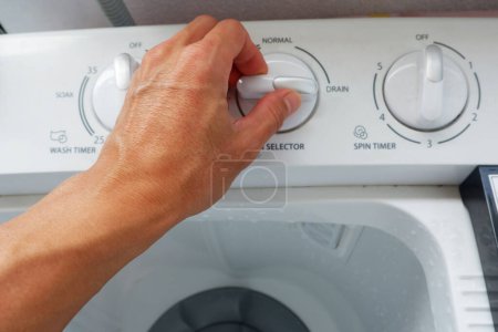 Foto de La mano de un hombre está girando la perilla de ajuste del tipo de lavado de una lavadora. - Imagen libre de derechos