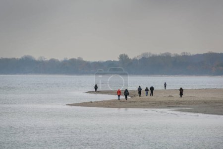 Foto de Personas que toman un paseo de otoño en la playa de Travemunde en el mar Báltico en un día gris de noviembre, espacio para copiar, enfoque seleccionado, estrecha profundidad de campo - Imagen libre de derechos