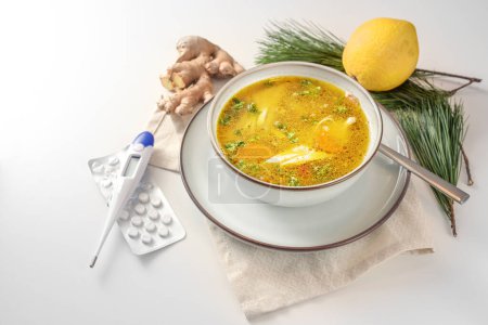 Photo for Stay healthy in the cold and flu season with chicken soup, ginger and lemon as home remedies, fiber thermometer and tablets for medical care, light background, copy space, selected focus - Royalty Free Image