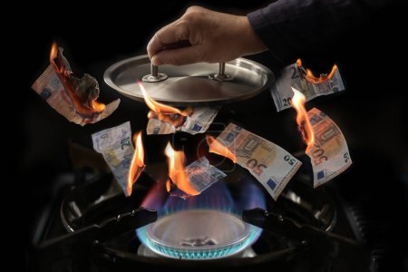 Gaspreisdeckel-Konzept, Herd mit Flammen, brennende Euro-Banknoten fliegen nach oben, Hand hält Topfdeckel darüber, um den Preisanstieg in der Energiekrise zu begrenzen, dunkler Hintergrund