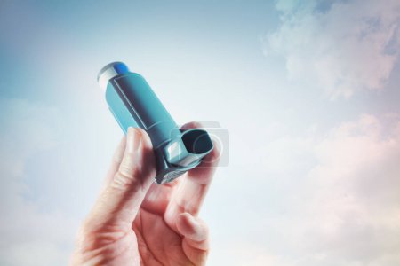 Photo for Hand holding an inhaler with spray as emergency medication for an asthma attack, allergy or other lung disease with shortness of breath, copy space, selected focus, narrow depth of field - Royalty Free Image