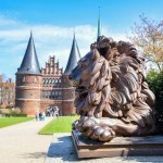 Lion statue from iron guards the Lubeck Holstentor or Holsten gate, historic landmark and tourist attraction under a blue sky, symbol of the old town of Luebeck, Germany, copy space, selected focus