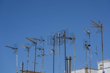Foto de Varias antenas en el techo de un edificio de apartamentos residenciales para la comunicación y los medios de comunicación, tales como televisión, Internet, teléfono inteligente y radio, cielo azul, espacio de copia, enfoque seleccionado - Imagen libre de derechos