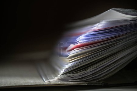 Photo for Close up of documents in transparent sleeves or punched pockets in a ring binder against a dark background, concept for office and business, copy space, selected focus, very narrow depth of field - Royalty Free Image