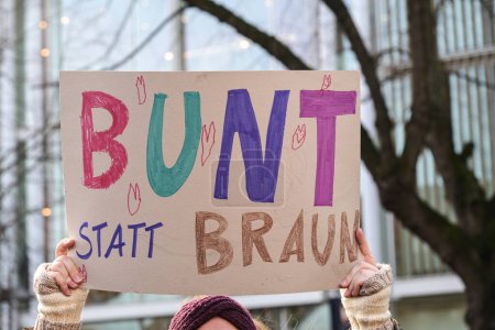 Photo for Woman holding a cardboard sign with the German text Bunt statt Braun (Colorful instead of Brown), as protest against racism and neo-Nazi fascism on a demonstration in Lubeck Germany, January 22, 2024 - Royalty Free Image