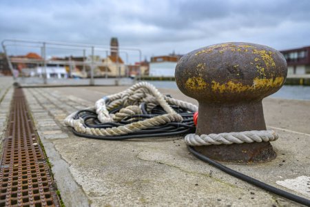 Pilona con cuerda y cable en el muelle en el puerto viejo en la ciudad hanseática de Wismar en el mar Báltico en Alemania, el turismo y el destino de viaje, cielo nublado, enfoque seleccionado, estrecha profundidad de campo