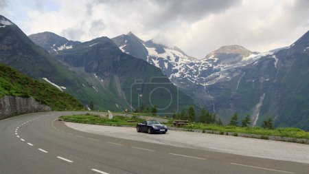 Foto de Fusch, Austria - 25 de julio de 2021: El roadster azul Porsche Boxster 986 con panorama de montaña y curva de horquilla en Grossglockner High Alpine Road. El coche es un coche deportivo fabricado por Porsche. - Imagen libre de derechos