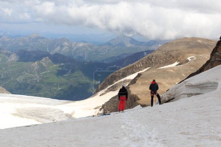 Téléchargez les photos : Deux alpinistes debout sur un glacier et regardant vers Grossglockner High Alpine Road et panorama de montagne à Glockner Group, Autriche - en image libre de droit