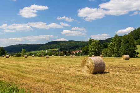 Rural scene with round hay bales and hill panorama near village Wannbach in Franconian Switzerland, Germany