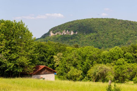 Ländliche Szene mit Hügel- und Felsenpanorama und Haus bei Wichsenstein in der Fränkischen Schweiz, Deutschland