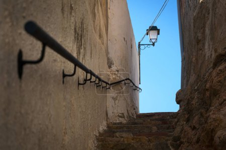 Foto de Calle estrecha con escaleras arriba y un poste de luz sobre el cielo azul en el fondo, Onda, Castellón, España - Imagen libre de derechos