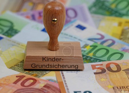 Photo for Wooden stamp with the imprint "Kindergrundsicherung", translation "child basic security" - Royalty Free Image