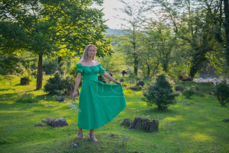 Photo for A young girl in a green dress jumps in a clearing. High quality photo - Royalty Free Image