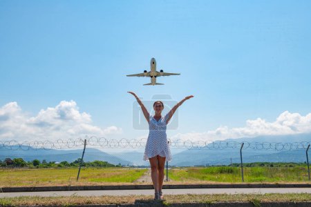 Photo for One girl in a white dress is standing on the road and stretching her hands in the sky towards the plane. High quality photo - Royalty Free Image