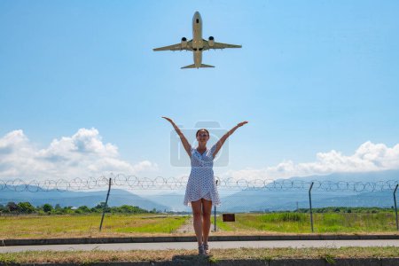 Photo for Standing on the road and stretching her hands in the sky to the plane one girl. High quality photo - Royalty Free Image
