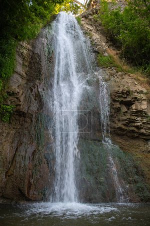 Photo for Against the background of green trees, the water of the waterfall flows. High quality photo - Royalty Free Image