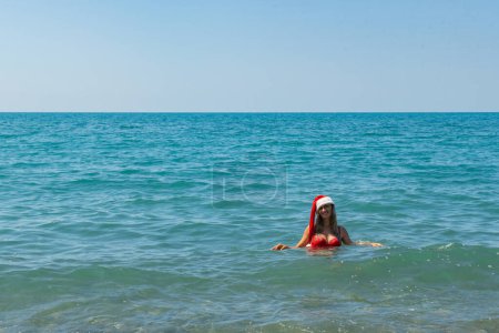 Photo for Santa Hat at the Shore: Red Swimsuit Ocean Adventure. High quality photo - Royalty Free Image