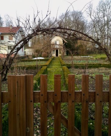 Téléchargez les photos : Une vieille maison abandonnée derrière un jardin froid et verdoyant pendant l'étreinte étrange de l'hiver - en image libre de droit