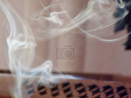 Téléchargez les photos : Gros plan de fumée d'encens émergeant de la boîte en bois avec des trous complexes - en image libre de droit