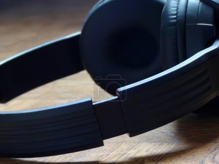 Photo for Closeup Composition: Cropped Black Headset Laid on Wood, Off-Frame Bleed with Tight Framing - Royalty Free Image