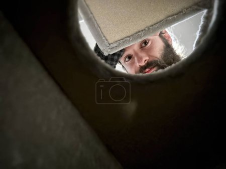 Mann mit Bart blickt durch ein Loch und bietet eine einzigartige und verspielte Perspektive