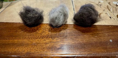 Three Balls of Cat Fur in Various Shades Laid Out on a Wooden Table