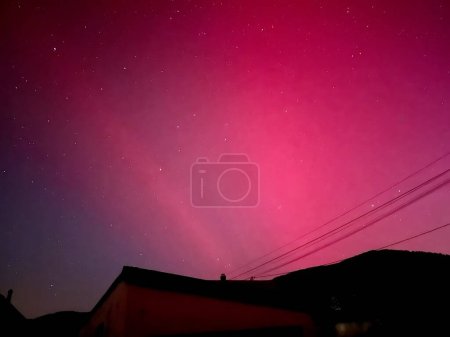 Majestic Pink Aurora Borealis Painting the Night Sky Over a Small Town During a Rare Solar Event in May 2024
