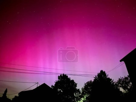 Téléchargez les photos : Superbe aurore boréale au-dessus de la France urbaine : un ciel violet et rose vif issu d'une éruption solaire sans précédent le 10 mai 2024 - en image libre de droit