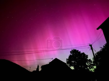 Téléchargez les photos : Superbe aurore boréale au-dessus de la France urbaine : un ciel violet et rose vif issu d'une éruption solaire sans précédent le 10 mai 2024 - en image libre de droit