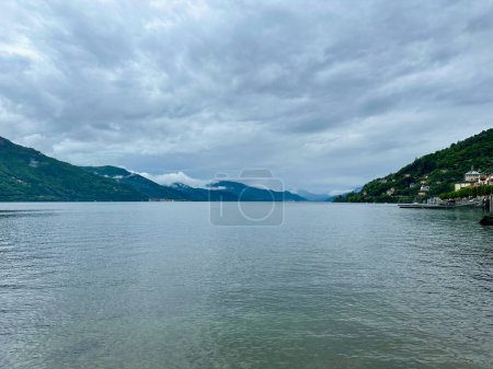 Ausgedehnte und friedliche Wasserlandschaft des Lago Maggiore, von Cannobio aus mit weit entfernten wolkenverhangenen Hügeln, Verbano-Cusio-Ossola, Piemont, Italien
