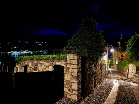 Scenic Nighttime View of Cobblestone Street Leading to Lake Orta in Orta San Giulio, Italy with Illuminated Path and Buildings