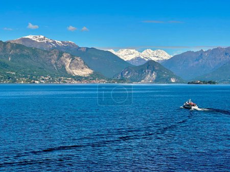 Malerischer Blick auf den Lago Maggiore mit schneebedeckter Weissmies-Bergkette und Boot in Baveno, Italien
