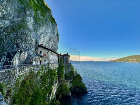 Panoramablick auf die Einsiedelei Santa Caterina del Sasso, die sich an die Klippe klammert und den weiten Lago Maggiore überblickt