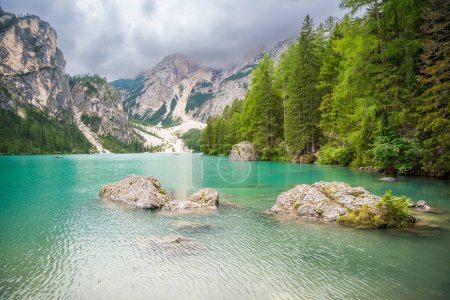 Foto de Lago Braies rodeado de bosques de pinos y las cordilleras rocosas de los Dolomitas en el día nublado, Italia. Foto de alta calidad - Imagen libre de derechos