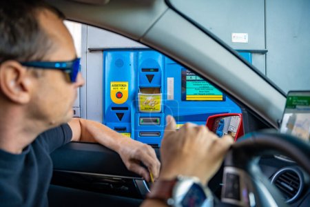 Téléchargez les photos : Tyrol du Sud, Italie - 3 août 2023 : Homme dans une voiture payant par carte à un péage italien pour utiliser l'autoroute ou Autostrade. Photo de haute qualité - en image libre de droit