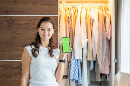 Foto de Mujer joven usando aplicación de teléfono inteligente para la venta de ropa vieja no deseada en la aplicación. Pantalla verde croma. Foto de alta calidad - Imagen libre de derechos