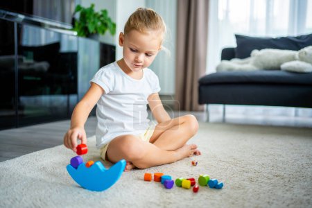 Foto de Niña jugando con el juguete de equilibrio de madera en el suelo en la sala de estar en casa. Foto de alta calidad - Imagen libre de derechos