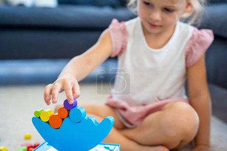 Foto de Niña jugando con el juguete de equilibrio de madera en el suelo en la sala de estar en casa. Concéntrate en equilibrador. Foto de alta calidad - Imagen libre de derechos