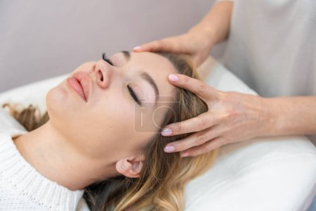 Healer performing by lightly touched set of 32 points of access bars on young woman head, stimulating positive change thoughts and emotions. Alternative medicine concept. High quality photo