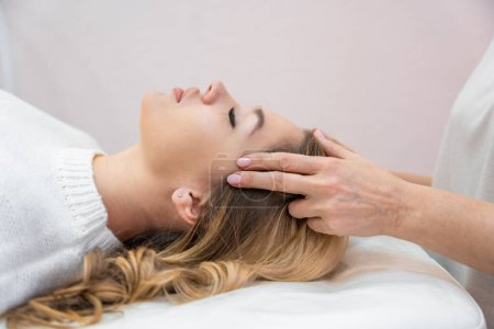 Healer performing by lightly touched set of 32 points of access bars on young woman head, stimulating positive change thoughts and emotions. Alternative medicine. High quality photo