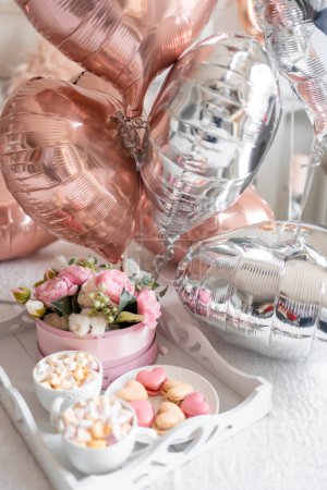 Photo for Flowers and sweets on white table and balloons on the white bed. Gift for Valentines day or March 8 or Mothers Day or birthday. High quality photo - Royalty Free Image