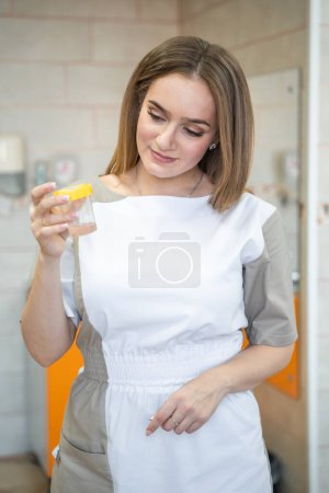 Foto de La trabajadora médica sostiene en su mano un pequeño recipiente con un trozo de piel extirpada preparado para el análisis de la gestología. Foto de alta calidad - Imagen libre de derechos