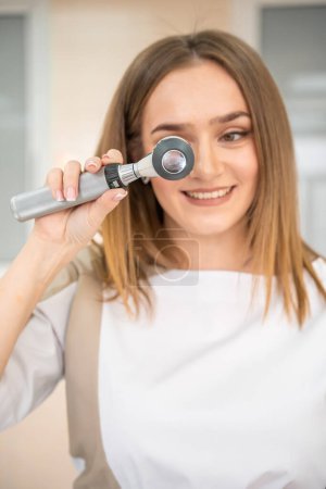 Portrait of woman dermatologist with dermatoscope in uniform and gloves in doctor office before examination in clinic. High quality photo