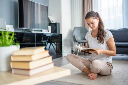 Young woman reading book and stack of books in the foreground. High quality photo