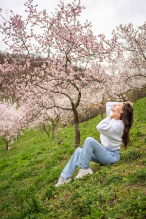 Lovely young woman in a blooming pink and white garden Petrin in Prague, spring time in Europe. High quality photo