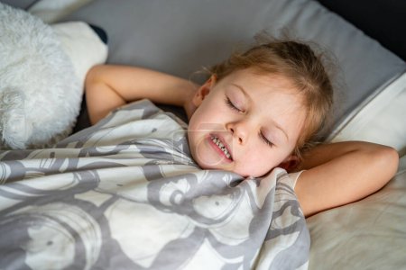 Téléchargez les photos : Petite fille mignonne dormant et grincant des dents dans les rêves, les dents serrées avec fatigue et stress. Photo de haute qualité - en image libre de droit