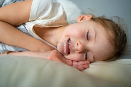 Téléchargez les photos : Petite fille mignonne dormant et grincant des dents dans les rêves, les dents serrées avec fatigue et stress. Photo de haute qualité - en image libre de droit
